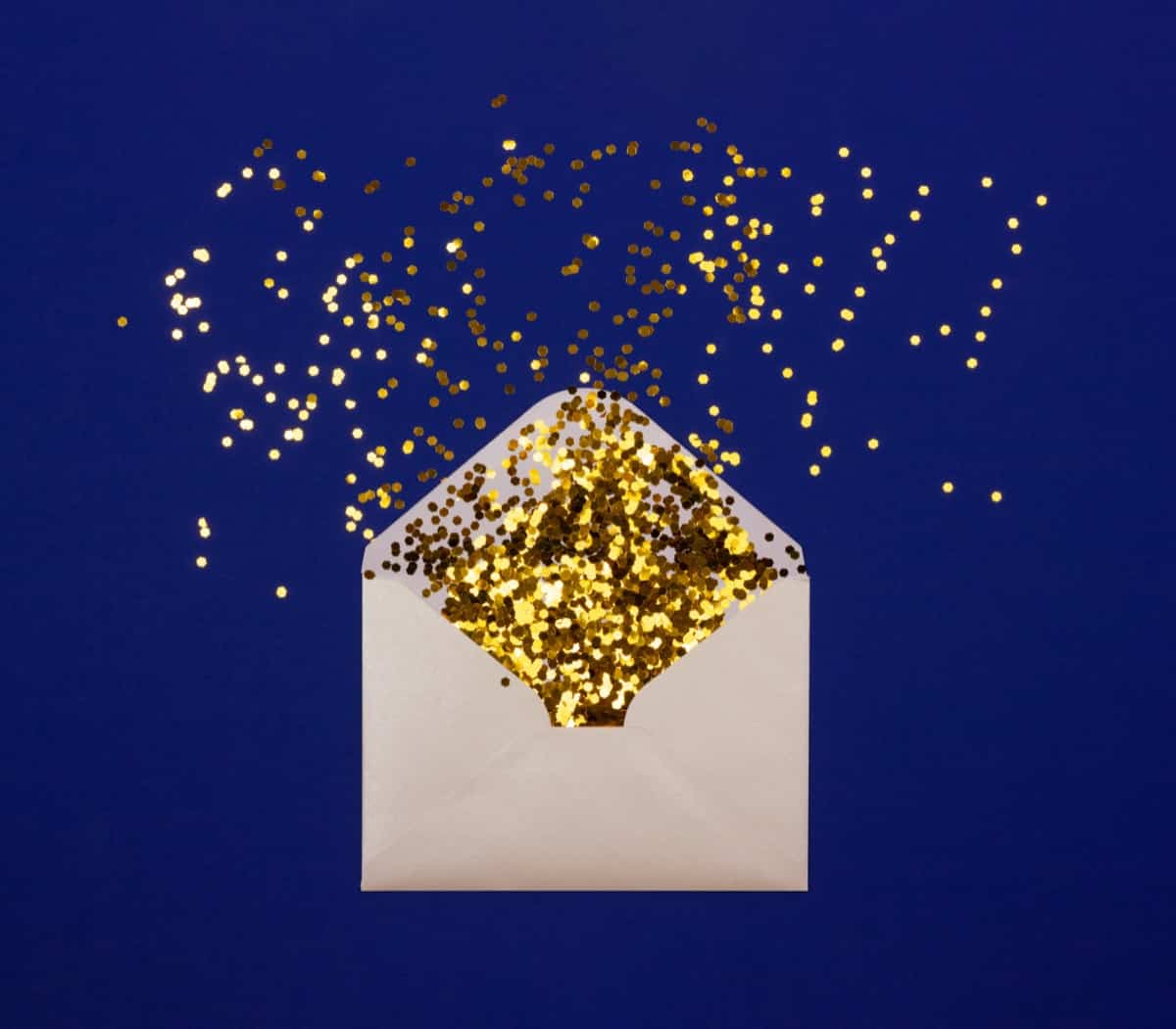 Envelope full of gold glitter against blue background