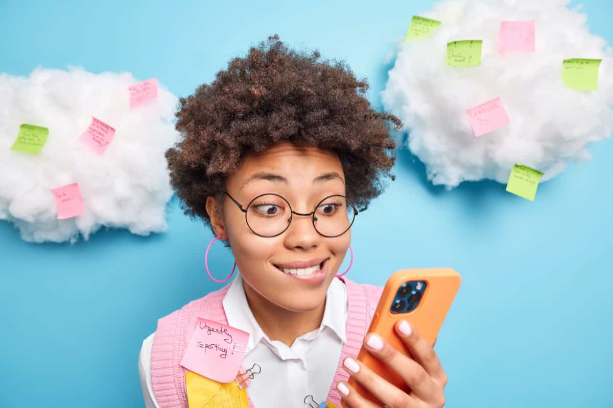 Young woman holding phone and wearing Post-It notes